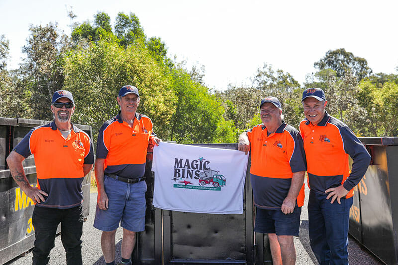 Team standing next to magic bins