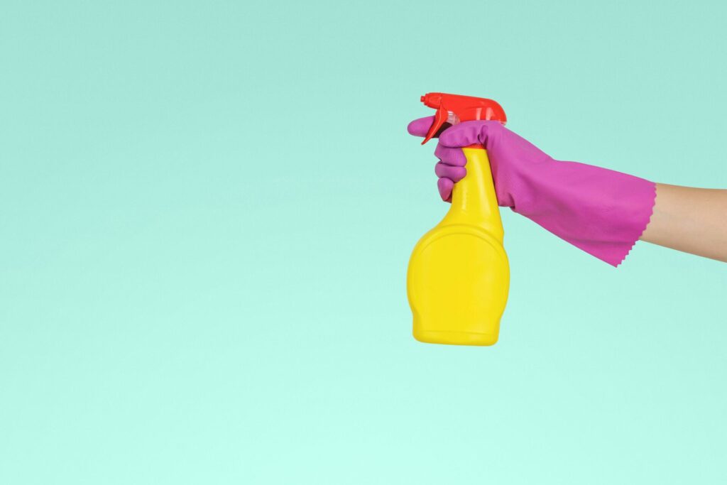 blue background, pink glove, and yollow and red spray bottle. 