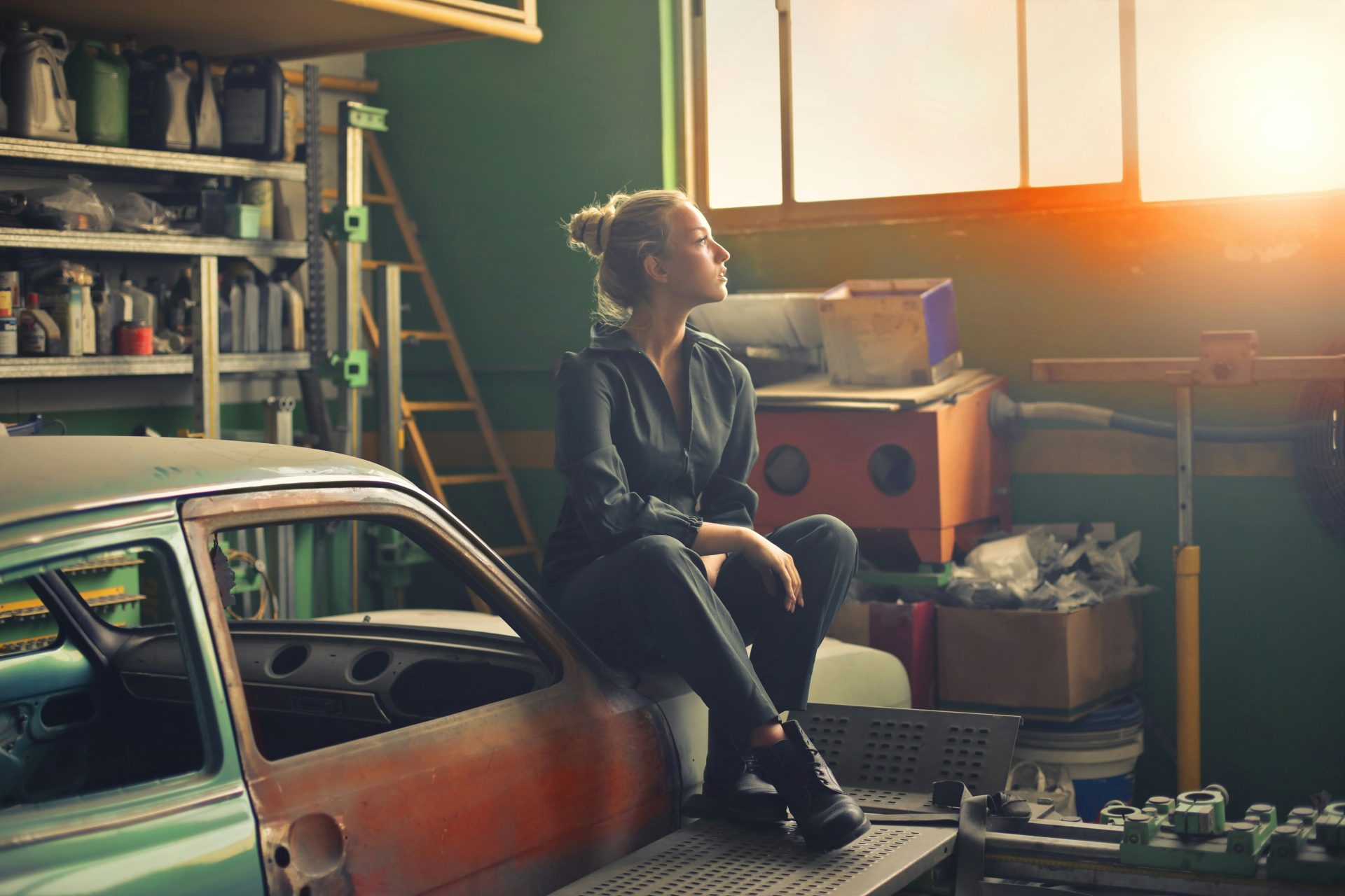 Woman sitting on car in garage